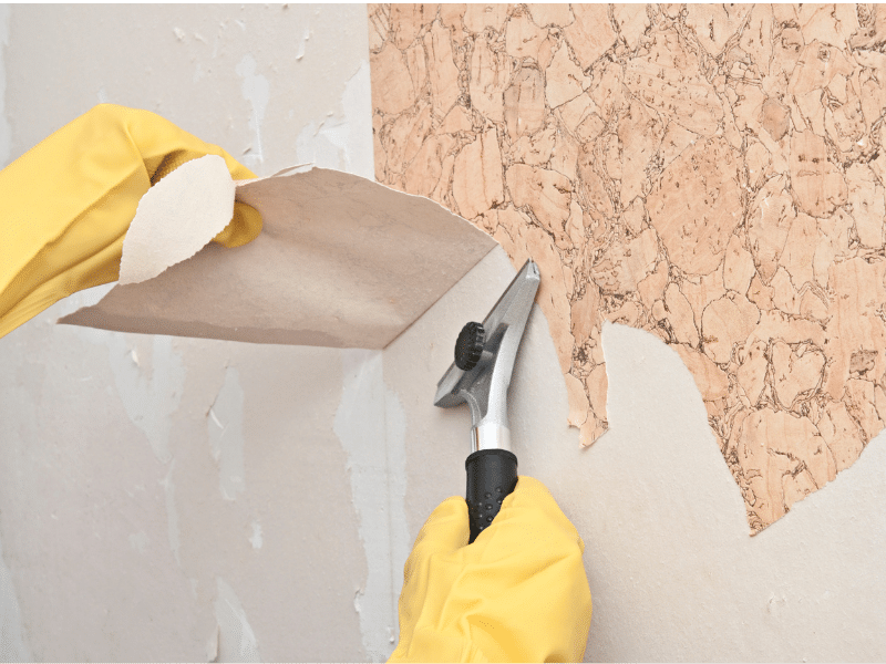 Professional removing stubborn wallpaper adhesive with specialized solution